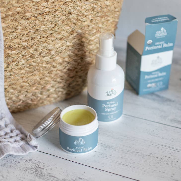 image of bottle of perineal balm, perineal spray and packaging next to brown woven basket.