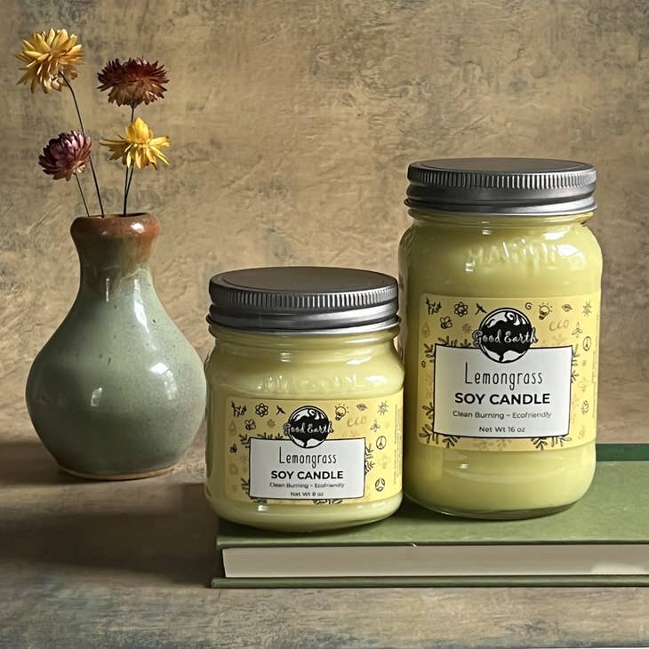 image of lemongrass soy candles in mason jars sitting on a book with flowers in the background.
