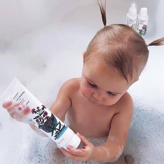 image of baby in tub holding bottle of organic VIVAIODAYS 2 in 1 body wash and shampoo.