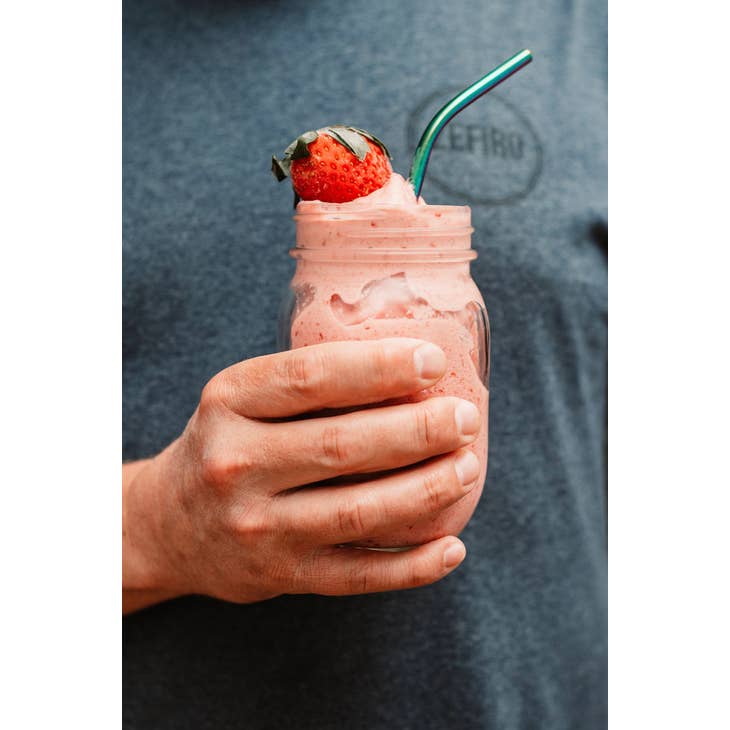 Image of person holding a mason jar with a drink in it, it has a stainless straw that is rainbow colored.