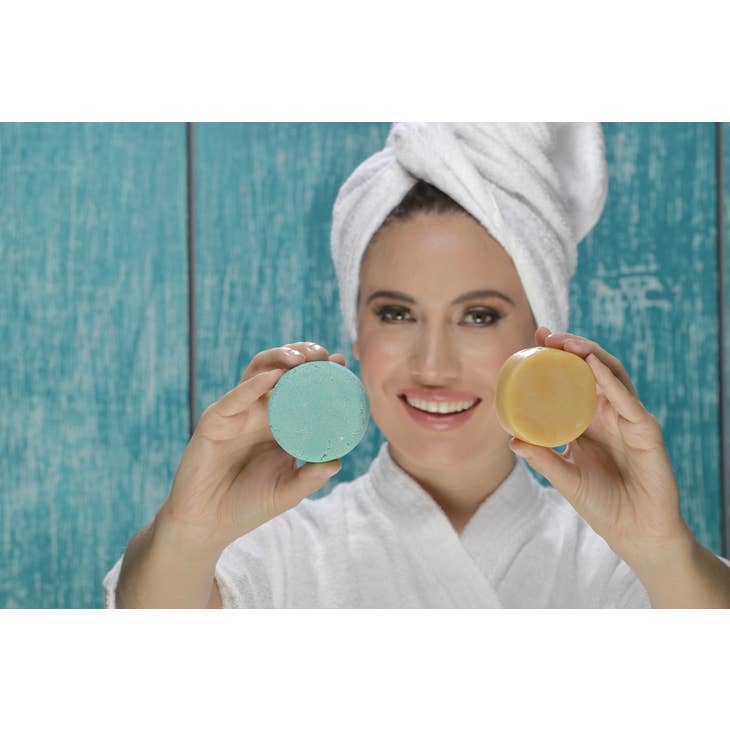 Image of woman holding a shampoo bar in one hand and a conditioner bar in the other