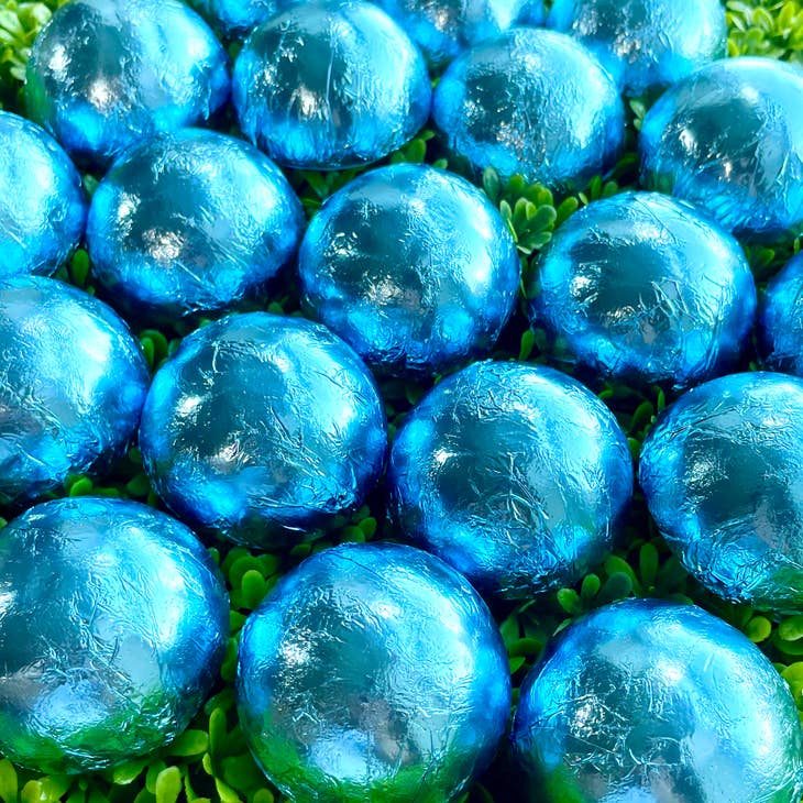 image of several blue foil wrapped shower steamers sitting on greenery.