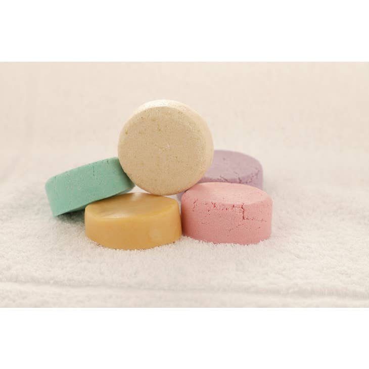 Image of 5 unpackaged shampoo and conditioner bars on a towel